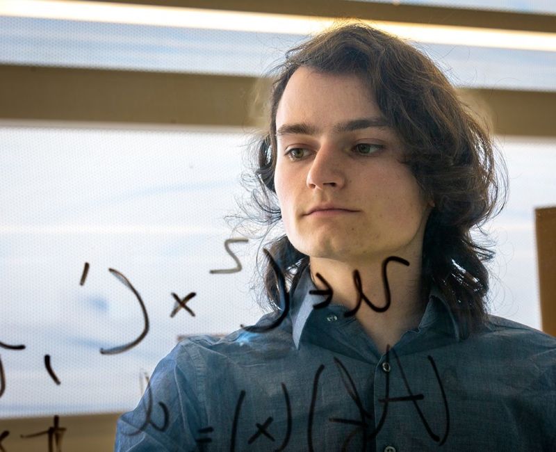 Student writes equations on whiteboard