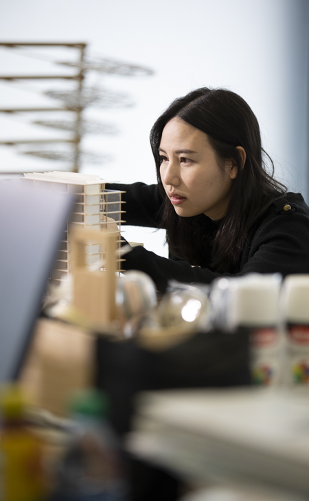 An architecture student studies a 3-d model at College of Architecture