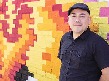 Juan De La Mora in front of one of his mural