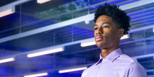 Male student standing in front of blue light glass