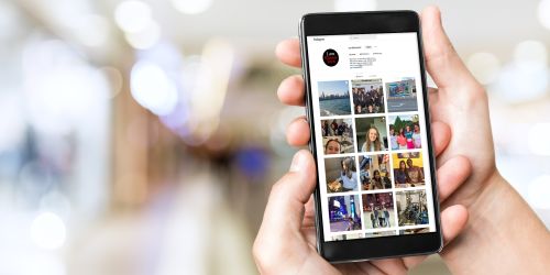 Hands hold a smartphone. On the screen display is the instagram account @iamillinoistech