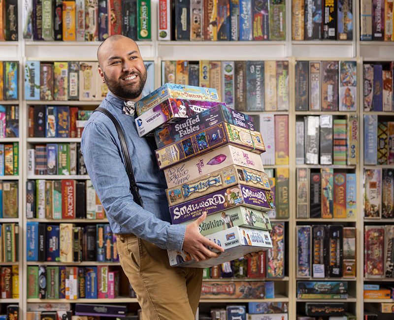 Illinois Tech alum Michael Deanda poses with games in a game store in Chicago